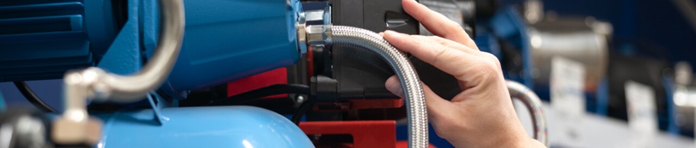Detailní pohled na instalaci vodního čerpadla pro automatický zavlažovací systém – propojení s hadicí a odborná montáž.