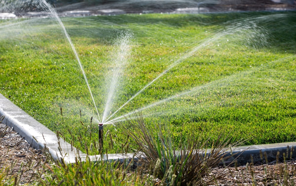 Automatický výsuvný postřikovač zavlažující trávník u rodinného domu